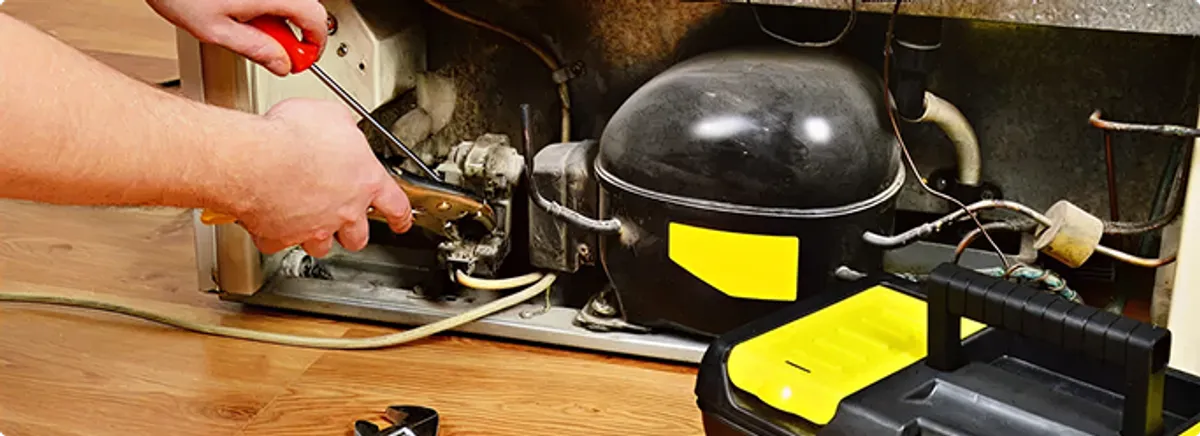 Refrigerator repair technician fixing the compressor and wiring in Longmont, CO