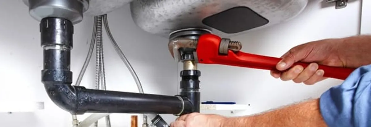 Garbage disposal repair technician tightening the sink drain and disposal connection in Boulder, CO