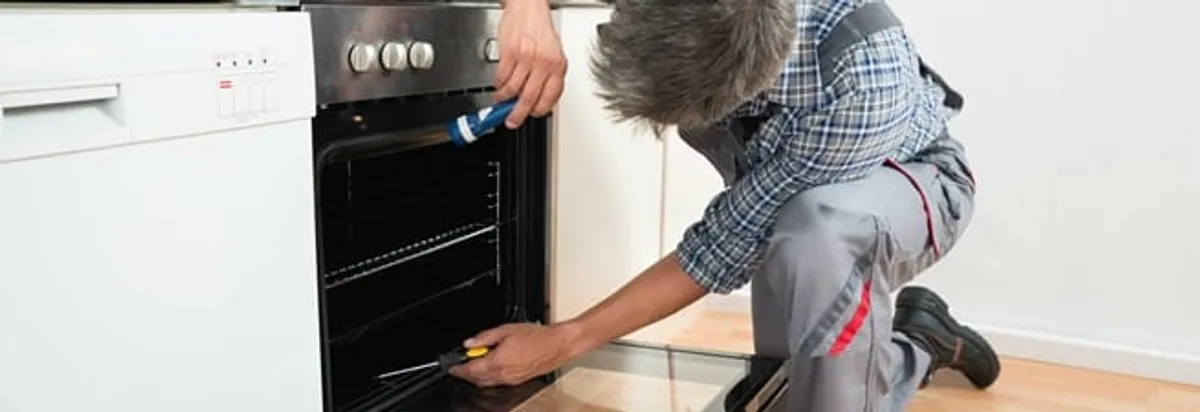 Oven repair technician inspecting and servicing an electric oven in Boulder, CO