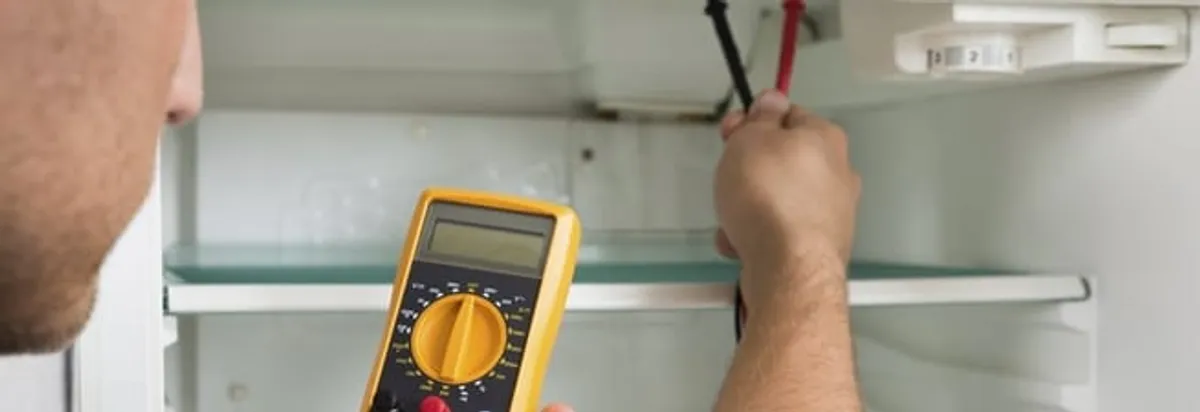 Refrigerator repair technician testing electrical components with a multimeter in Boulder, CO